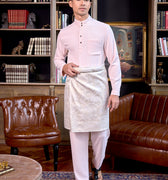 man wearing soft pink baju melayu set stands confidently