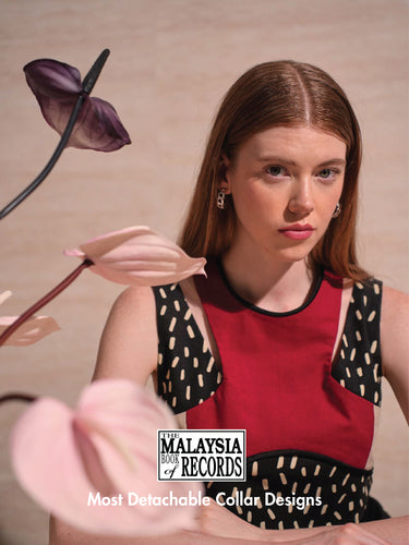 Women wearing black and red collar with prints posing in front of flower