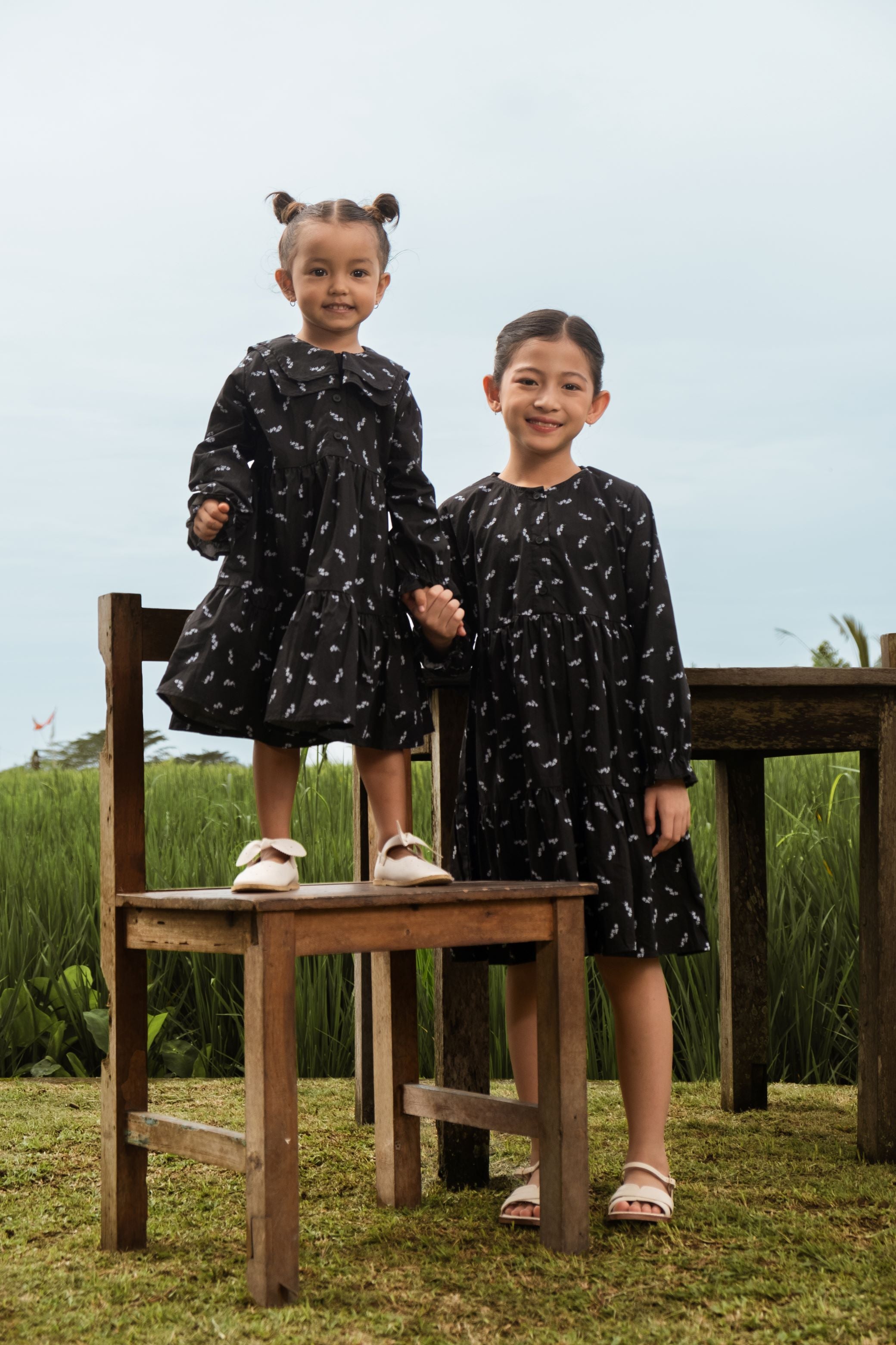 smiling sisters standing posing in holiday dress melati print