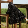 cute little girl in melati print holiday dress climbing chair