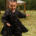 happy little girl running, wearing holiday dress melati print