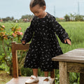 little girl standing on chair wearing melati print holiday dress