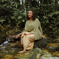 smiling woman sitting on rock, wearing 2-in-1 kebaya top green dahlia print