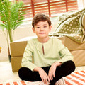 5-6 years old boy sitting cross-legged on the floor donning mint green teluk belanga top