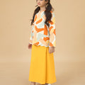 girl looking upwards and posing sideways in kurung top with scallop embroidery marmalade print