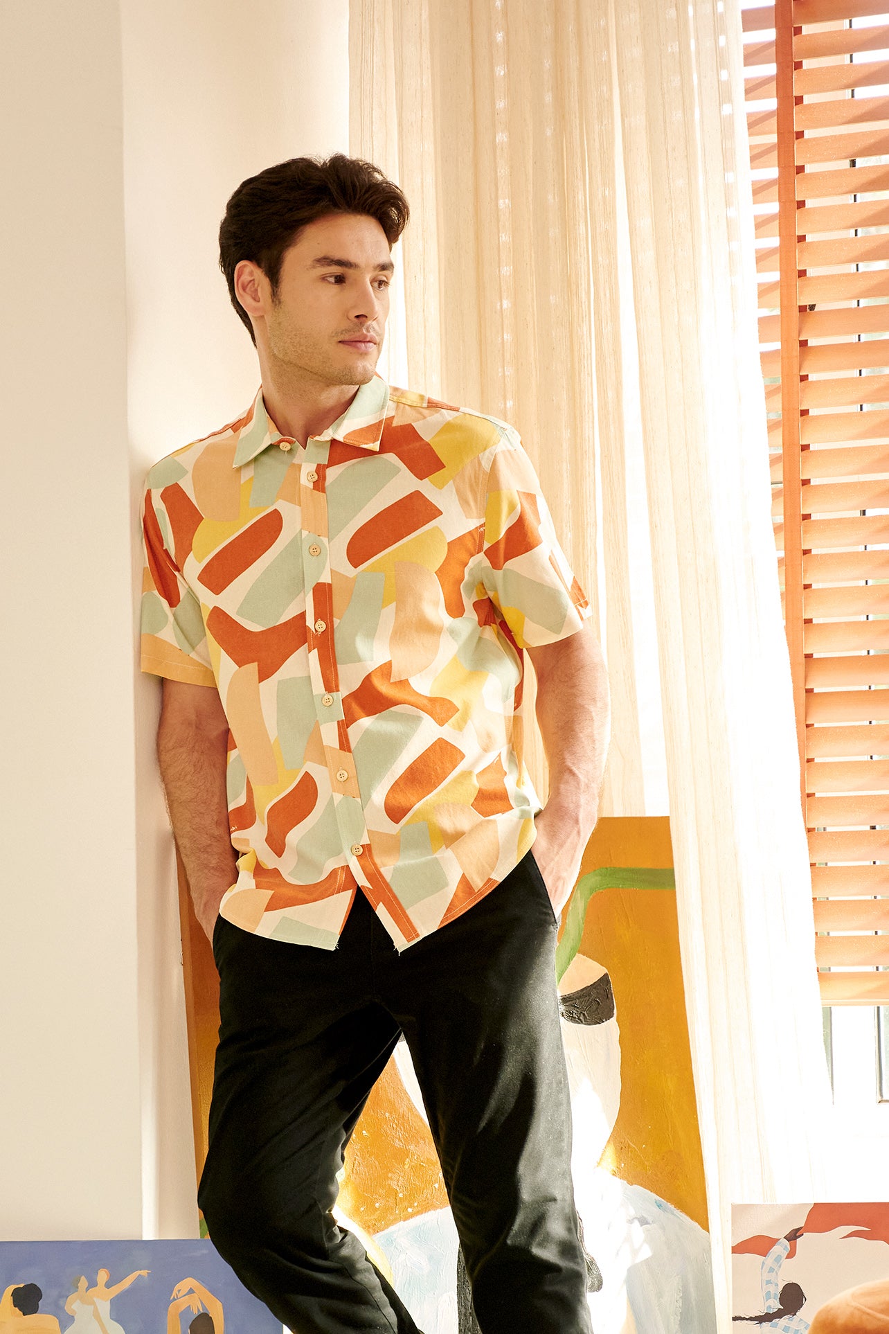 close shot of man in marmalade print holiday shirt leaning to the wall