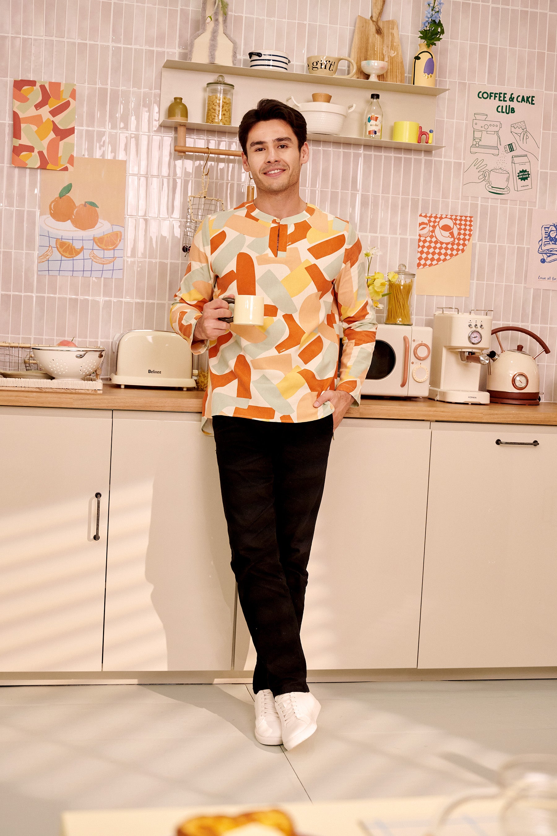 man in teluk belanga marmalade print posing while holding mug