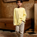 young boy with one hand in pocket posing in boy long sleeve kurta butter yellow