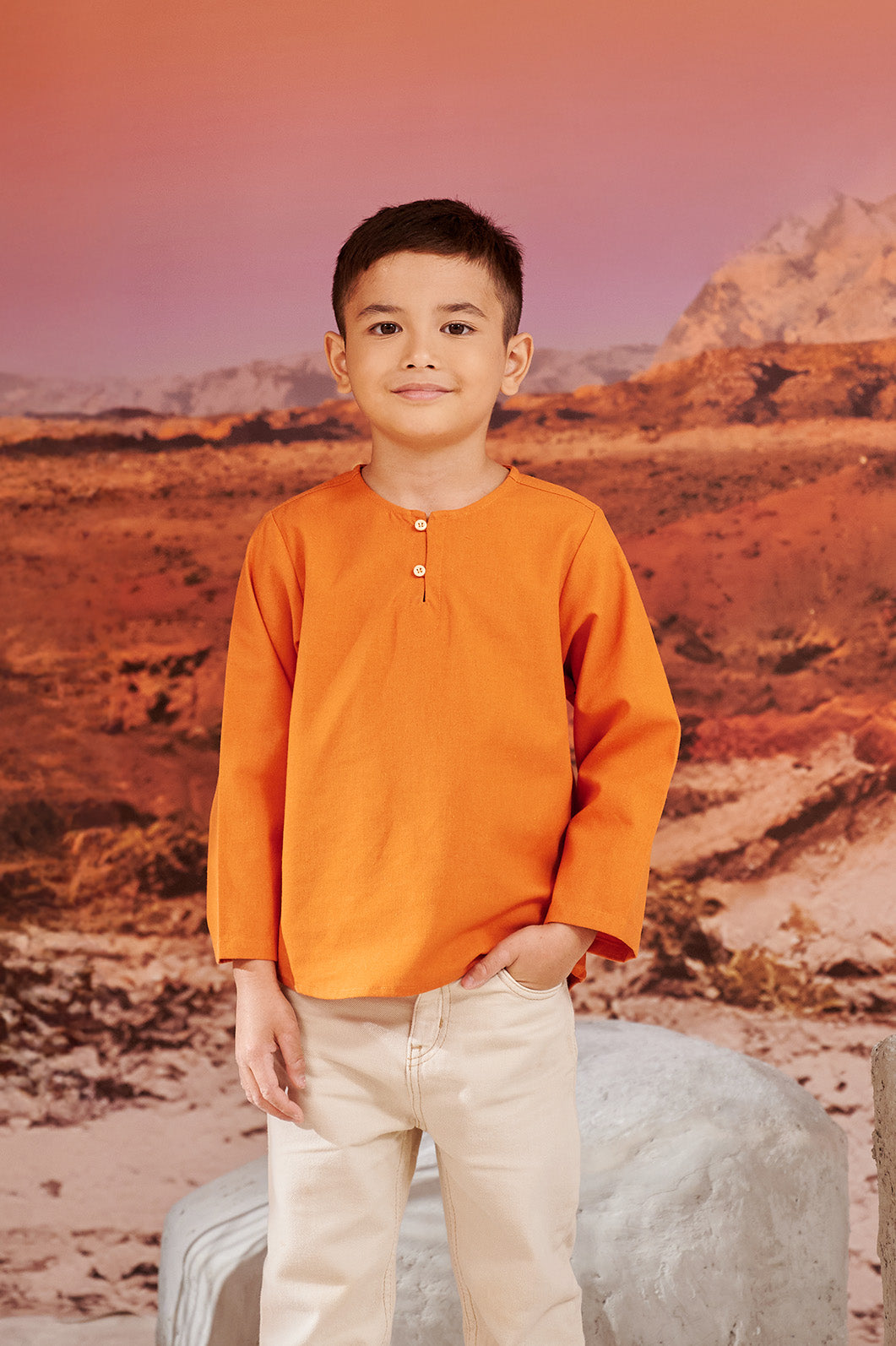 little boy smiling looking at camera wearing orange kurta top