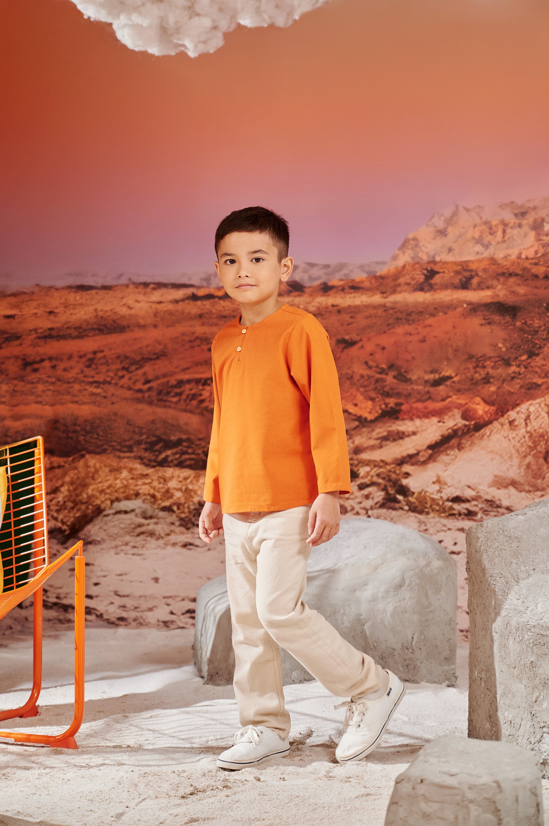 young boy looking at camera posing in kurta orange