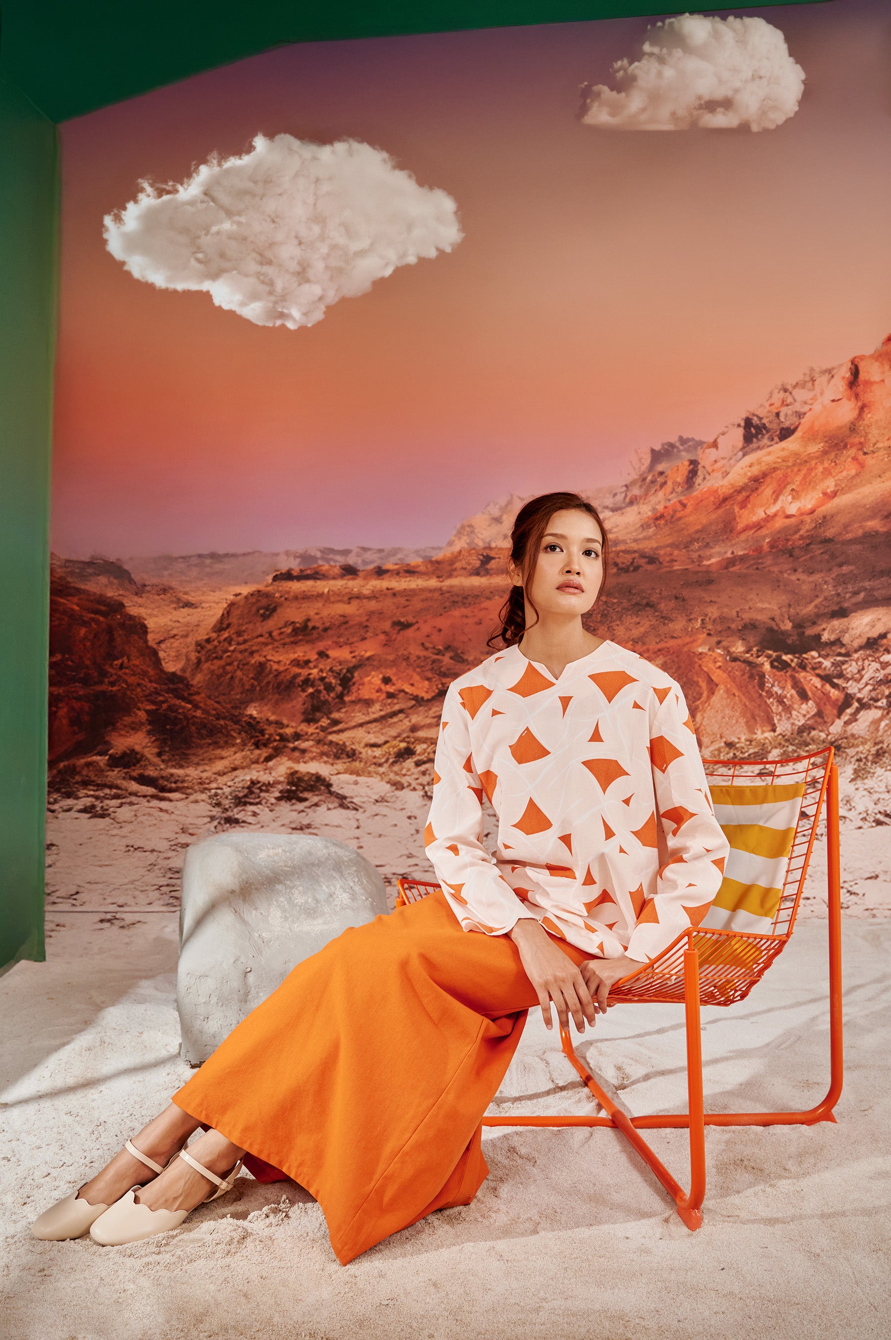 woman sitting on chair wearing desert print kurung top with scallop embroidery