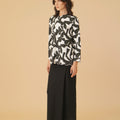 woman posing sideways wearing shadow print kurung top with scallop embroidery