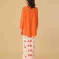 woman posing backwards in orange mandarin collar kurung top