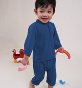 happy baby boy wearing steel blue baby baju melayu set, playing toys