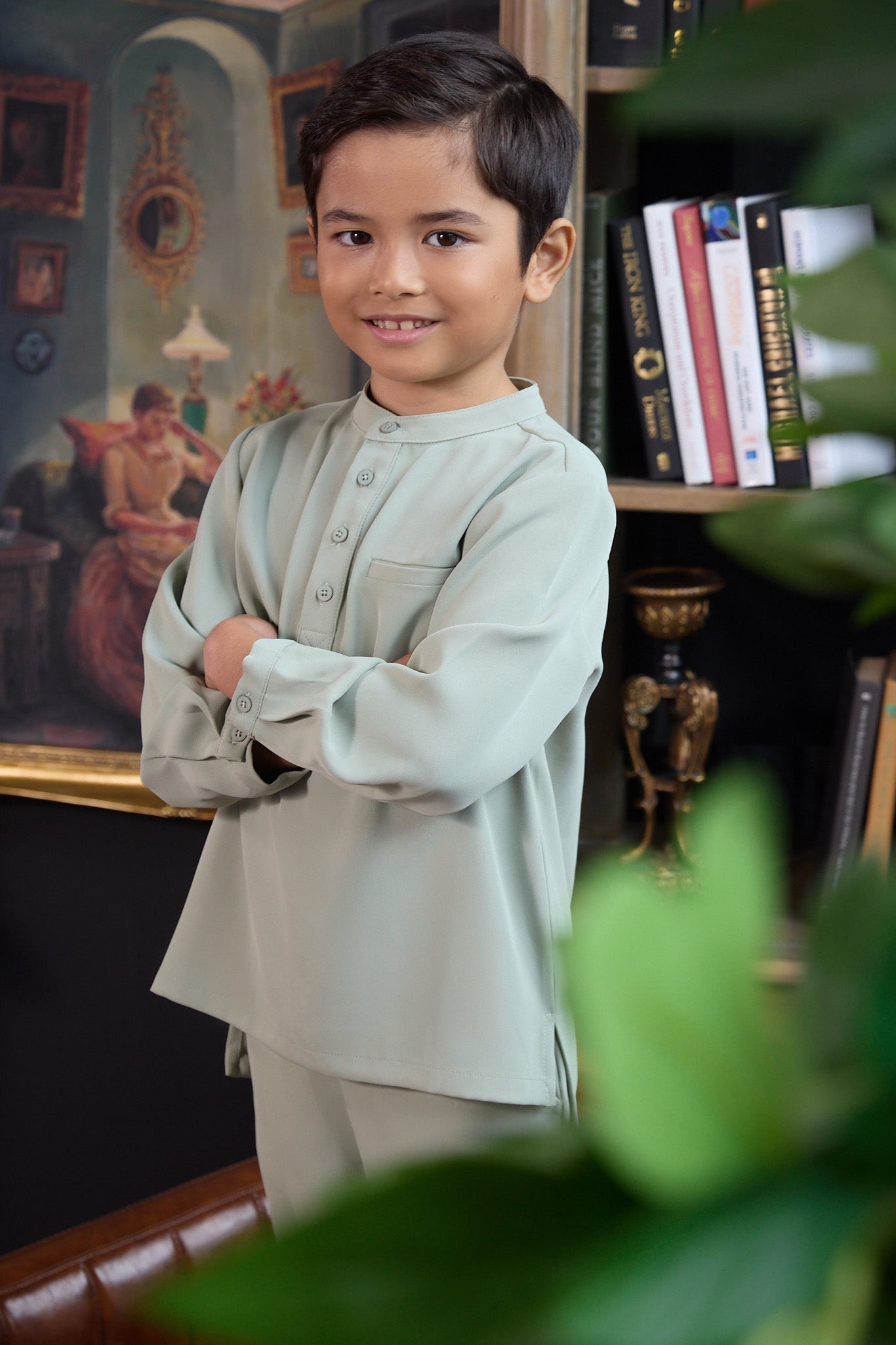 young boy with arms crossed posing wearing boy baju melayu set sage green