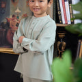 young boy with arms crossed posing wearing boy baju melayu set sage green