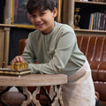 young smiling boy posing in sage green boy baju melayu set while playing chess