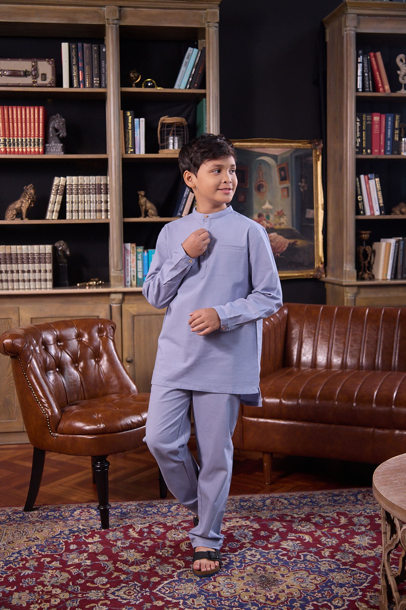 young boy holding placket, wearing stone blue boy baju melayu set