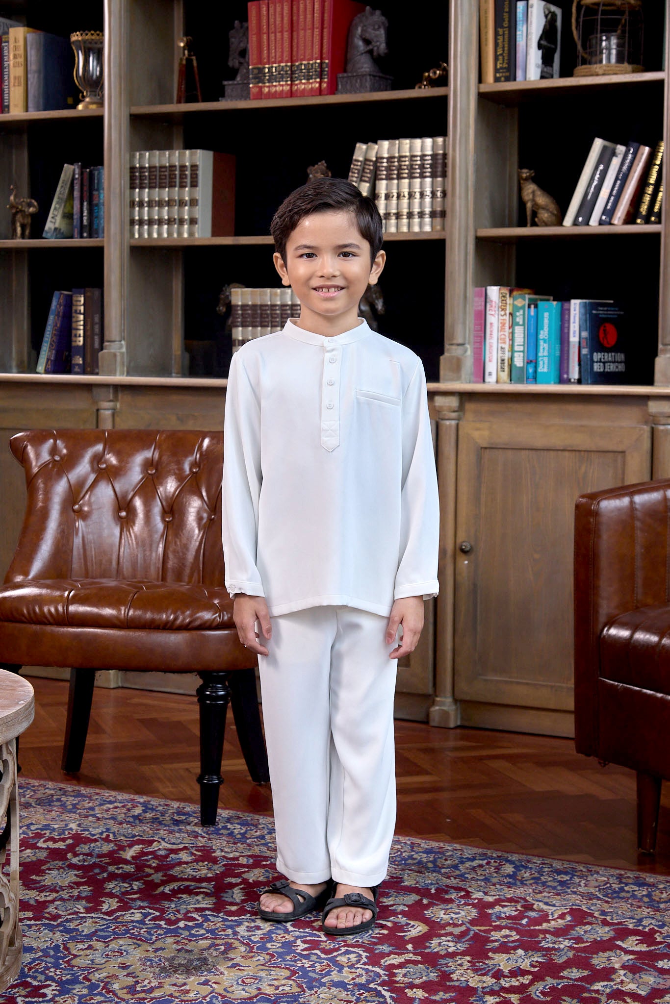 little boy smiling and standing pose in boy baju melayu set white