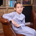 little girl sitting on sofa posing in stone blue girl kurung top