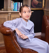 little girl sitting on sofa posing in stone blue girl kurung top