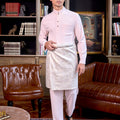 man wearing soft pink baju melayu set stands confidently