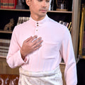 man donning soft pink baju melayu set stands posing confidently