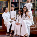 whole family dressed in white attire from warisan raya collection, sitting together and posing for the camera