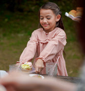 girl in checked red dress serving cupcake