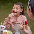 girl eating strawberry in checked red dress