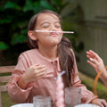 girl playing with straw at the tea party in checked red dress